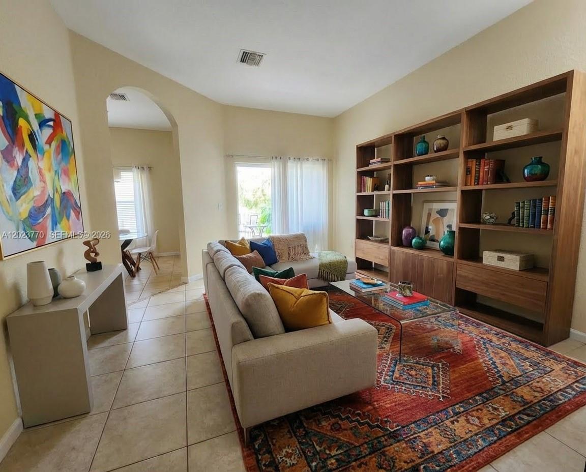 A living room features a large wooden bookshelf, a beige sectional sofa, and a patterned rug — 2363 SE 19th St, Homestead FL 33035, HOMESTEAD, FL