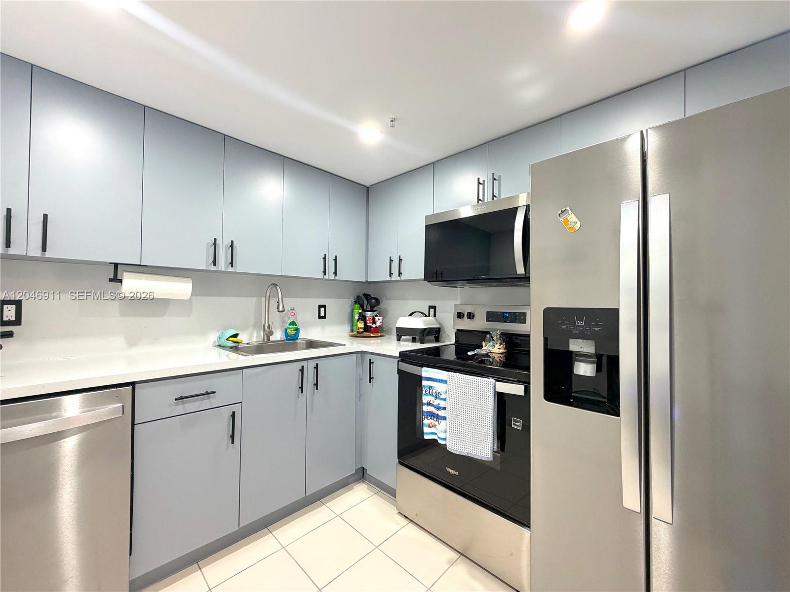 A kitchen features light blue cabinets, stainless steel appliances, and white countertops — 2829 Indian Creek Dr # 605, Miami Beach FL 33140, MIAMI BEACH, FL
