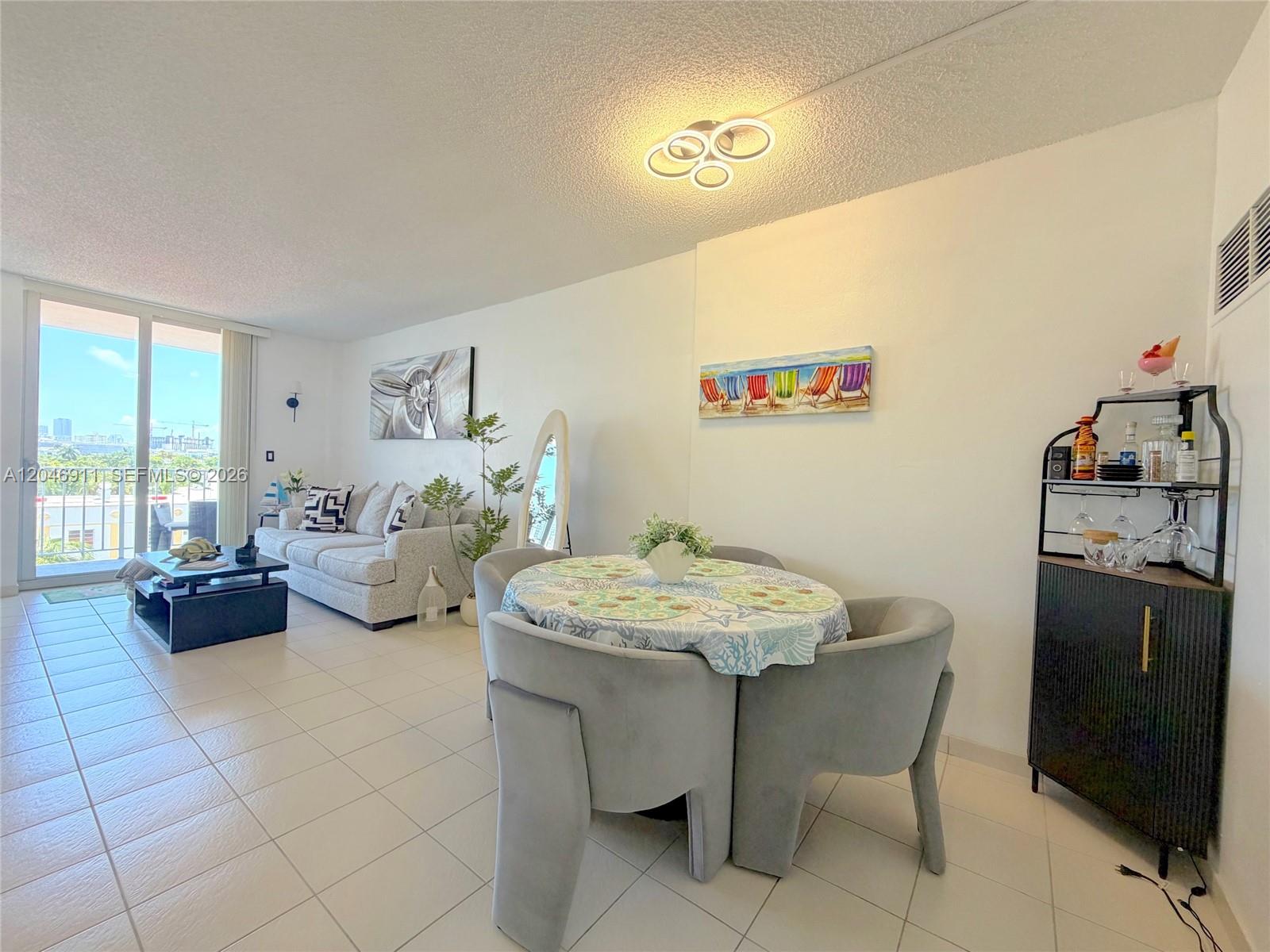 A living and dining area features tile floors, a sofa, and a round dining table — 2829 Indian Creek Dr # 605, Miami Beach FL 33140, MIAMI BEACH, FL