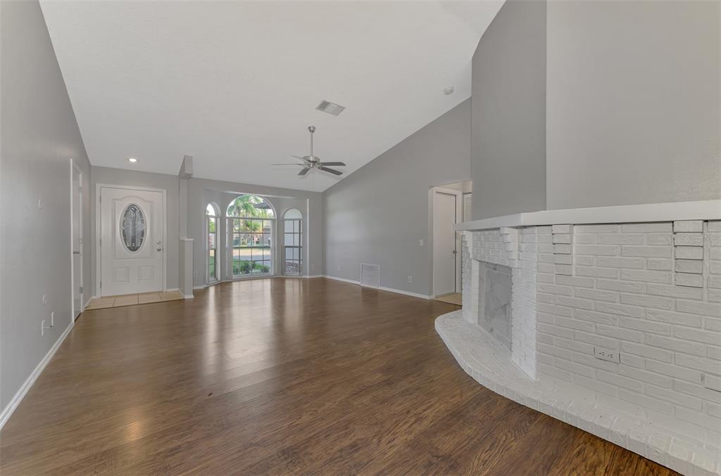A living room features wood-look flooring, a white brick fireplace, and a vaulted ceiling — 3026 GRAFTON STREET, SARASOTA, FL