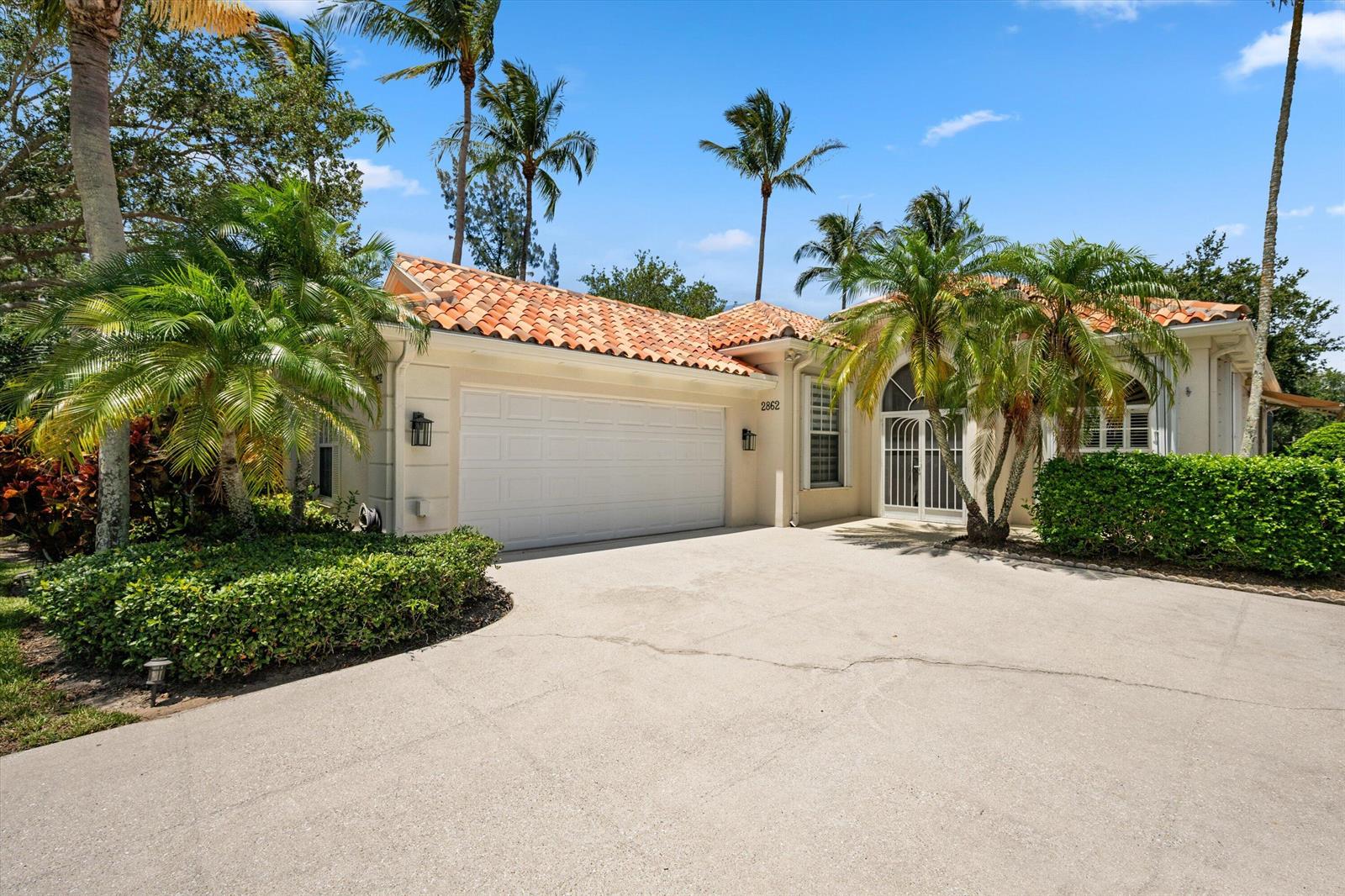 A single-story house with a tile roof, two-car garage, and palm trees in the front — 2862 Irma Lake Drive, West Palm Beach FL 33411, WEST PALM BEACH, FL
