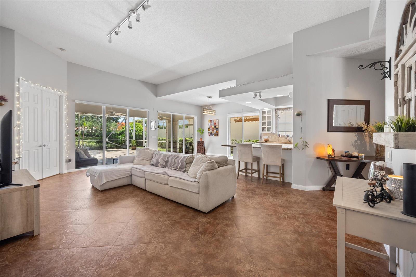 A living room with tile floors, a sectional sofa, and an open kitchen with bar seating — 2862 Irma Lake Drive, West Palm Beach FL 33411, WEST PALM BEACH, FL