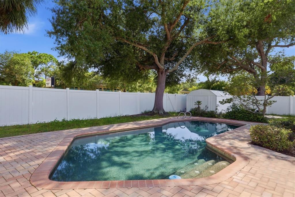 A backyard swimming pool with a brick paver deck, white vinyl fence, and large trees — 4420 W BAY COURT AVENUE, TAMPA, FL