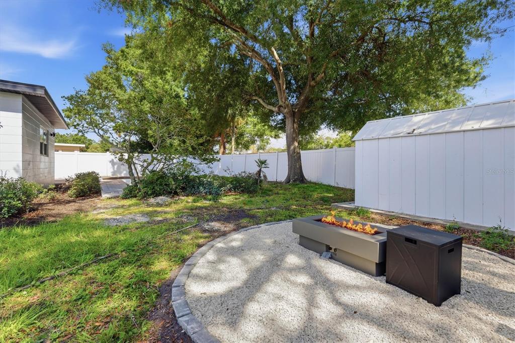 A backyard features a gravel fire pit area, a white shed, and a large tree — 4420 W BAY COURT AVENUE, TAMPA, FL