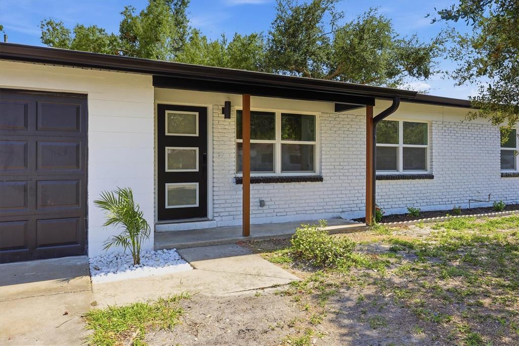A white brick house exterior features a dark front door, a garage, and a porch — 4420 W BAY COURT AVENUE, TAMPA, FL