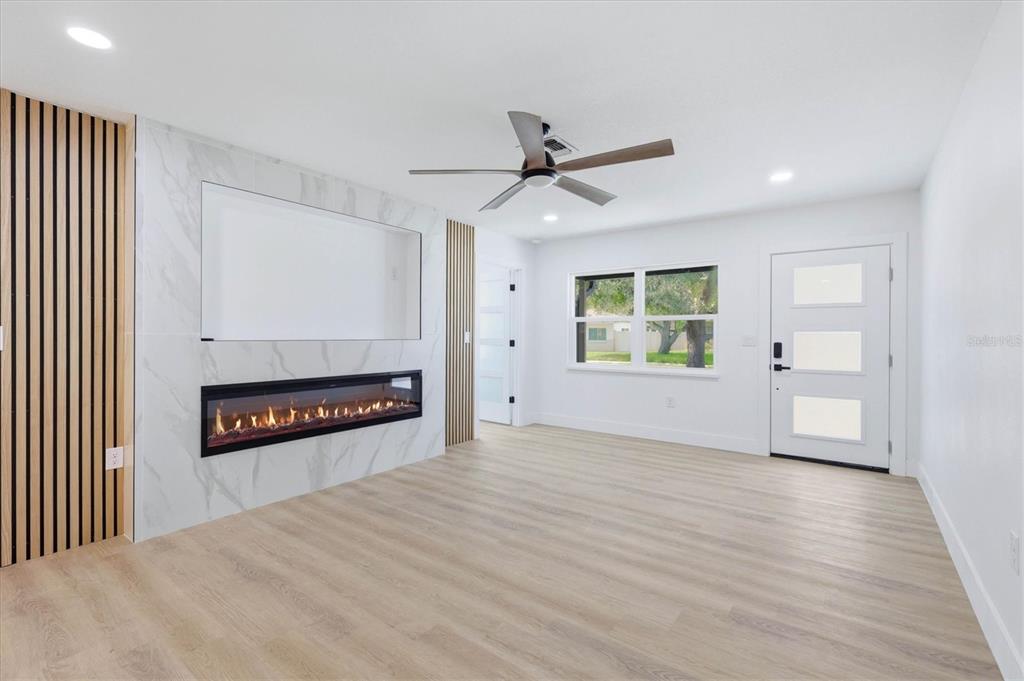 A living room features light wood flooring, a marble fireplace wall, and a ceiling fan — 4420 W BAY COURT AVENUE, TAMPA, FL