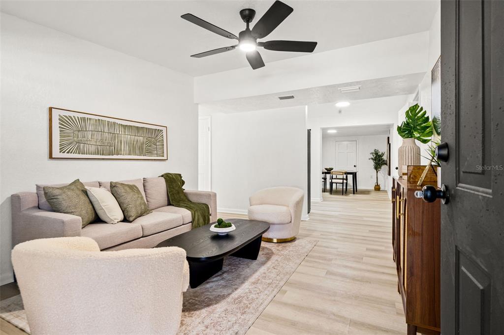 A living room features a light-colored sofa, two armchairs, a coffee table, and wood-look flooring — 4914 S 82ND STREET, TAMPA, FL