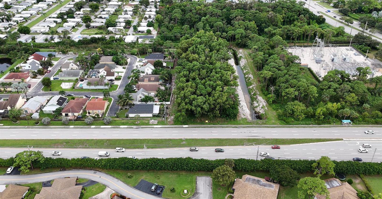 An aerial view shows a residential neighborhood, a wooded area, a canal, and a highway — 0000 Lantana Road, Atlantis FL 33462, ATLANTIS, FL