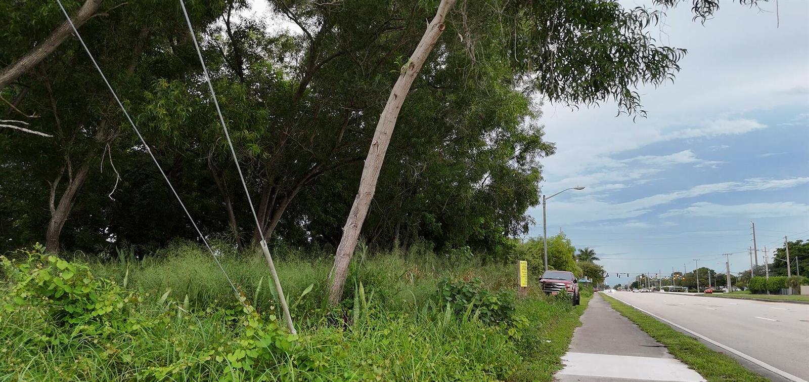A grassy, tree-lined lot sits adjacent to a sidewalk and a multi-lane road — 0000 Lantana Road, Atlantis FL 33462, ATLANTIS, FL