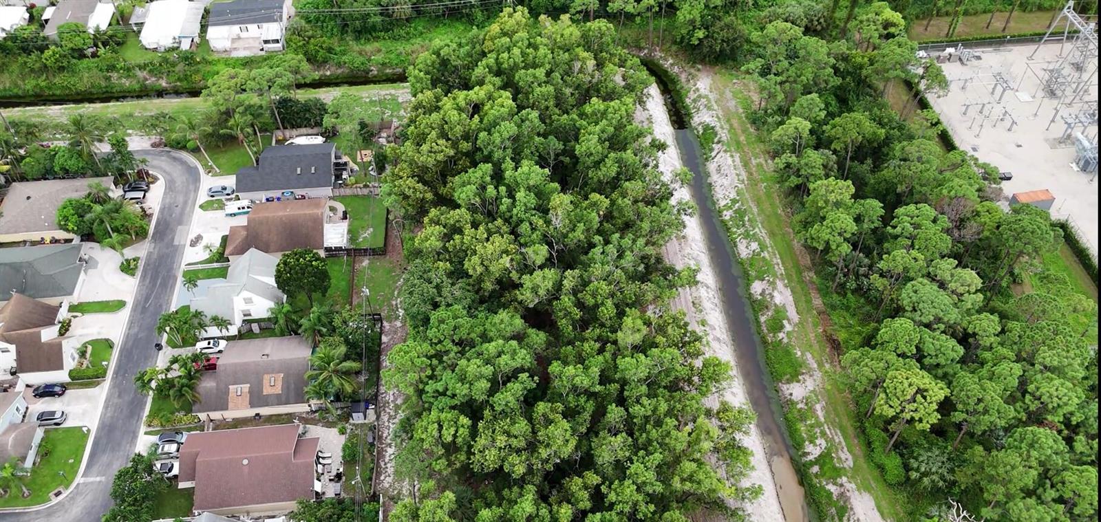 An aerial view shows a residential street bordering a wooded area and a drainage canal — 0000 Lantana Road, Atlantis FL 33462, ATLANTIS, FL
