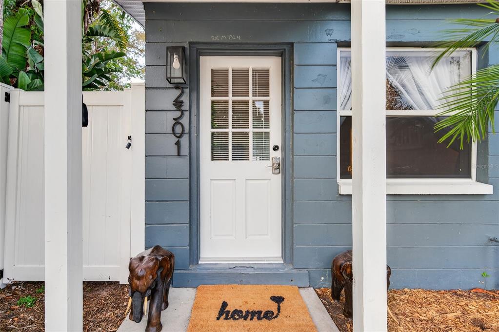 A blue-sided house exterior features a white front door, a welcome mat, and elephant statues — 2301 14TH AVENUE N, ST PETERSBURG, FL