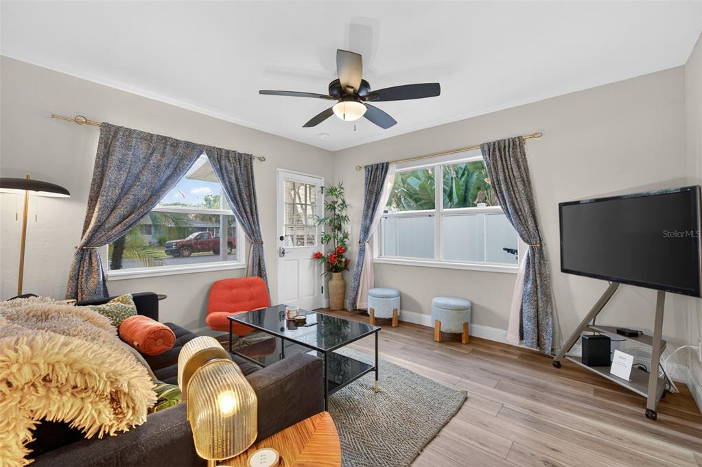 A living room features a ceiling fan, wood-look flooring, a television, and two windows — 2301 14TH AVENUE N, ST PETERSBURG, FL