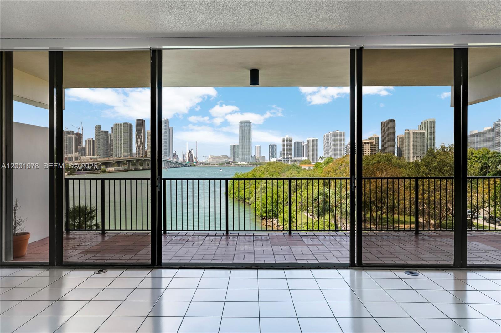 A tiled indoor room opens through sliding glass doors to a balcony overlooking a city skyline — 1000 Venetian Way # 408, Miami FL 33139, MIAMI, FL