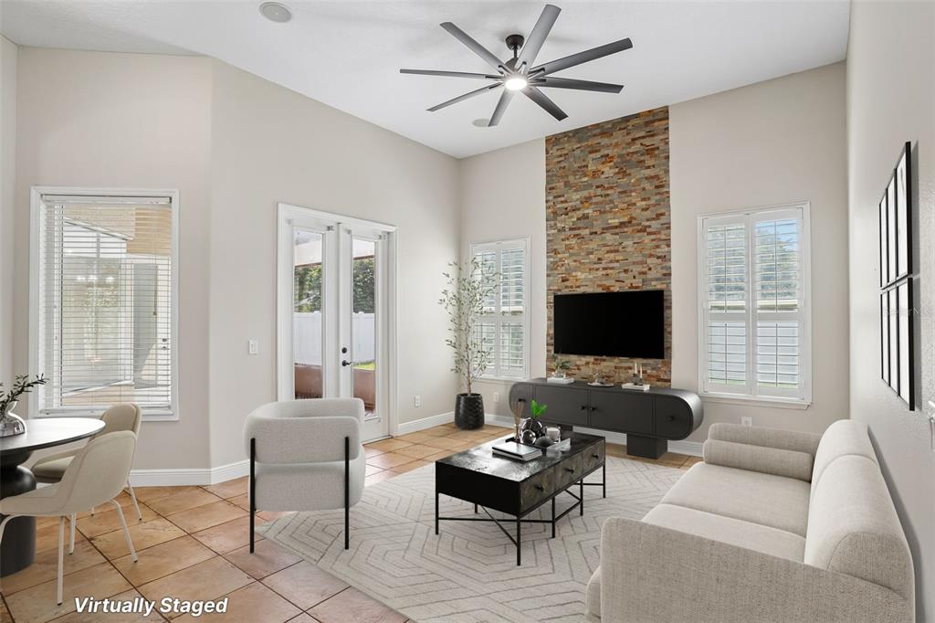 A living room features a stone accent wall, a ceiling fan, and tile flooring — 910 PARASOL PLACE, OVIEDO, FL