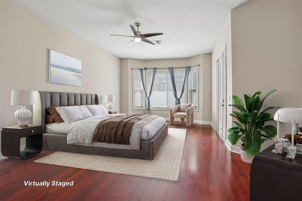 This virtually staged bedroom features hardwood floors, a bay window, and a ceiling fan — 910 PARASOL PLACE, OVIEDO, FL