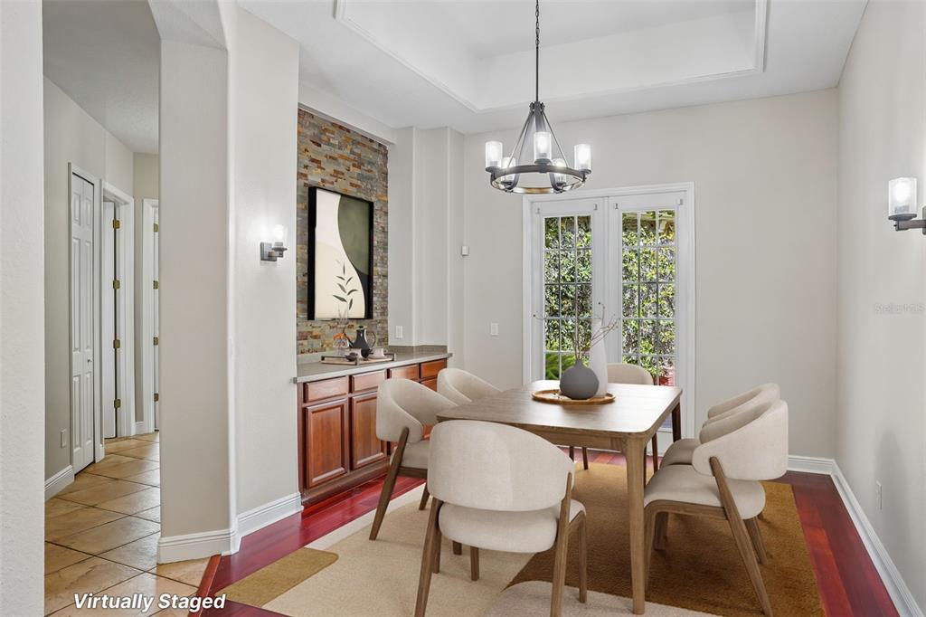 A dining room with a stone accent wall, wooden cabinets, and a chandelier over the table — 910 PARASOL PLACE, OVIEDO, FL
