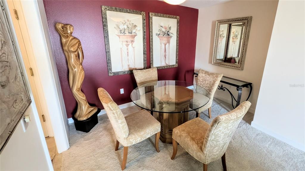 A dining area features a glass-topped table, four upholstered chairs, and a tall wooden sculpture — 750 N TAMIAMI TRAIL UNIT 1204, SARASOTA, FL