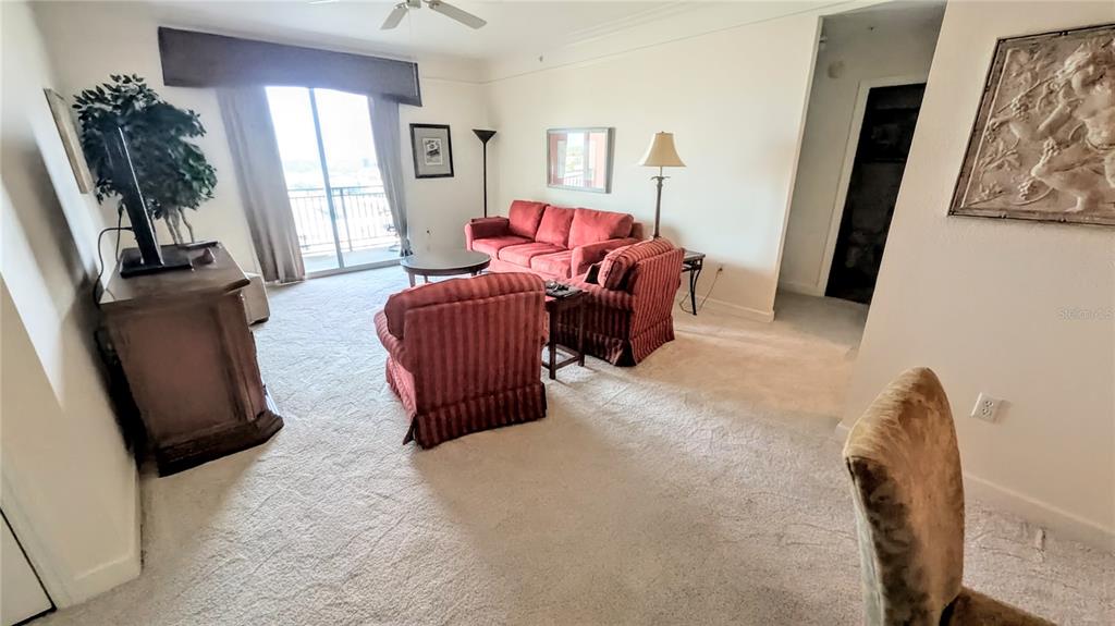 A living room features red upholstered furniture, beige carpeting, and a balcony with a view — 750 N TAMIAMI TRAIL UNIT 1204, SARASOTA, FL