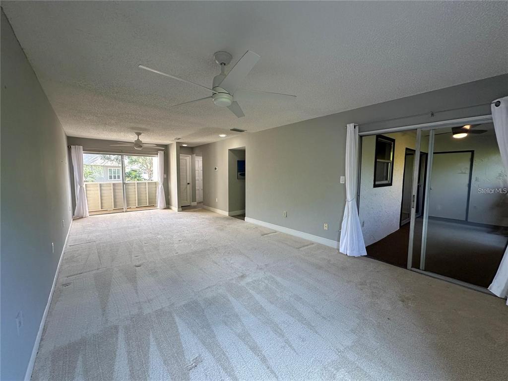 A sunroom with brown carpeting, a ceiling fan, and large windows overlooking trees — 514 WINDRUSH BAY DRIVE UNIT 514, TARPON SPRINGS, FL