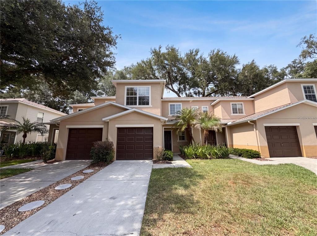 A two-story tan townhouse with brown garage doors and a concrete driveway — 2972 ROYAL TUSCAN LANE, VALRICO, FL