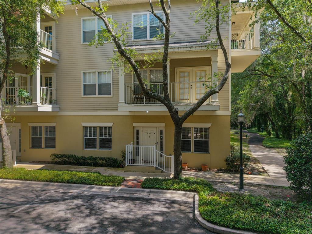 A three-story apartment building exterior with a ground-level entrance and upper-level balconies — 9177 SW 52ND ROAD UNIT E-103, GAINESVILLE, FL