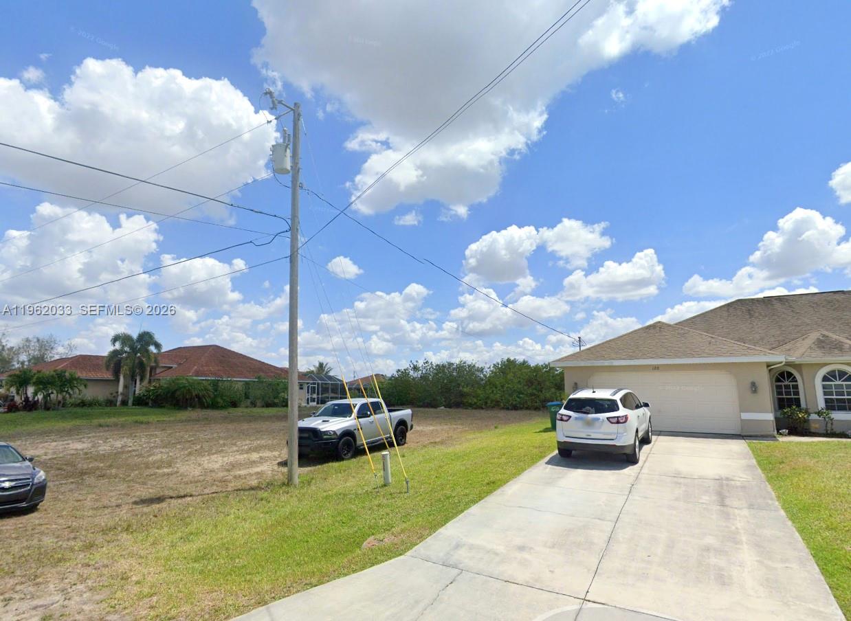 A white SUV is parked in the driveway of a single-story house with a garage — 124 NE 18TH ST, Cape Coral FL 33909, CAPE CORAL, FL