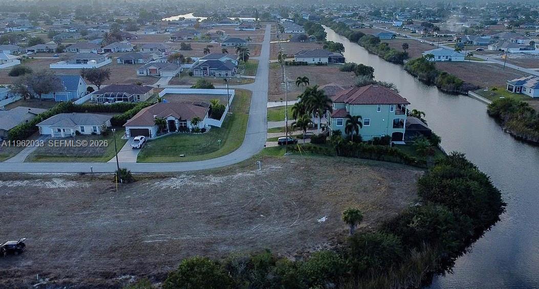 An aerial view shows a vacant lot next to a canal and residential houses — 124 NE 18TH ST, Cape Coral FL 33909, CAPE CORAL, FL