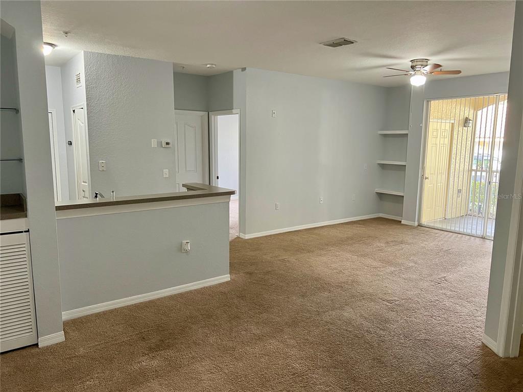 An interior view shows a carpeted living area with built-in shelves and a sliding glass door — 1100 LAKE SHADOW CIRCLE UNIT 2103, MAITLAND, FL