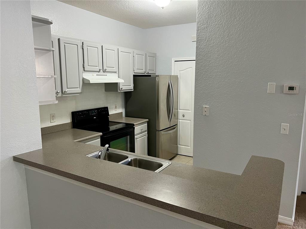 A kitchen features gray cabinets, stainless steel appliances, and a brown countertop breakfast bar — 1100 LAKE SHADOW CIRCLE UNIT 2103, MAITLAND, FL