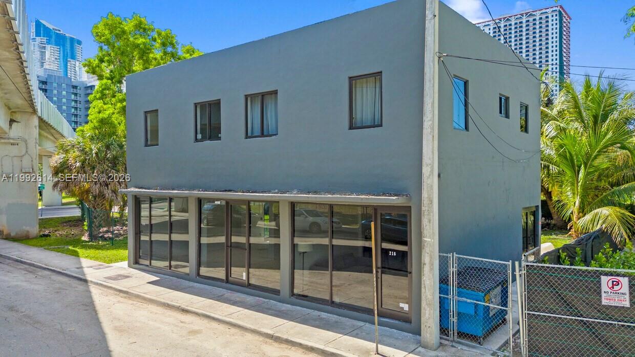A two-story gray commercial building with large glass windows and a front entrance door — 216 NW 11th St, Miami FL 33136, MIAMI, FL