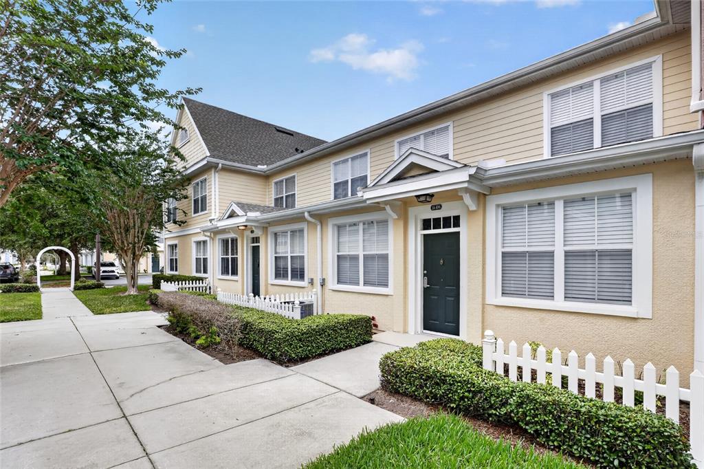 A two-story townhouse with yellow siding, white trim, and a small white picket fence — 4006 SAN GALLO DRIVE UNIT 104, KISSIMMEE, FL