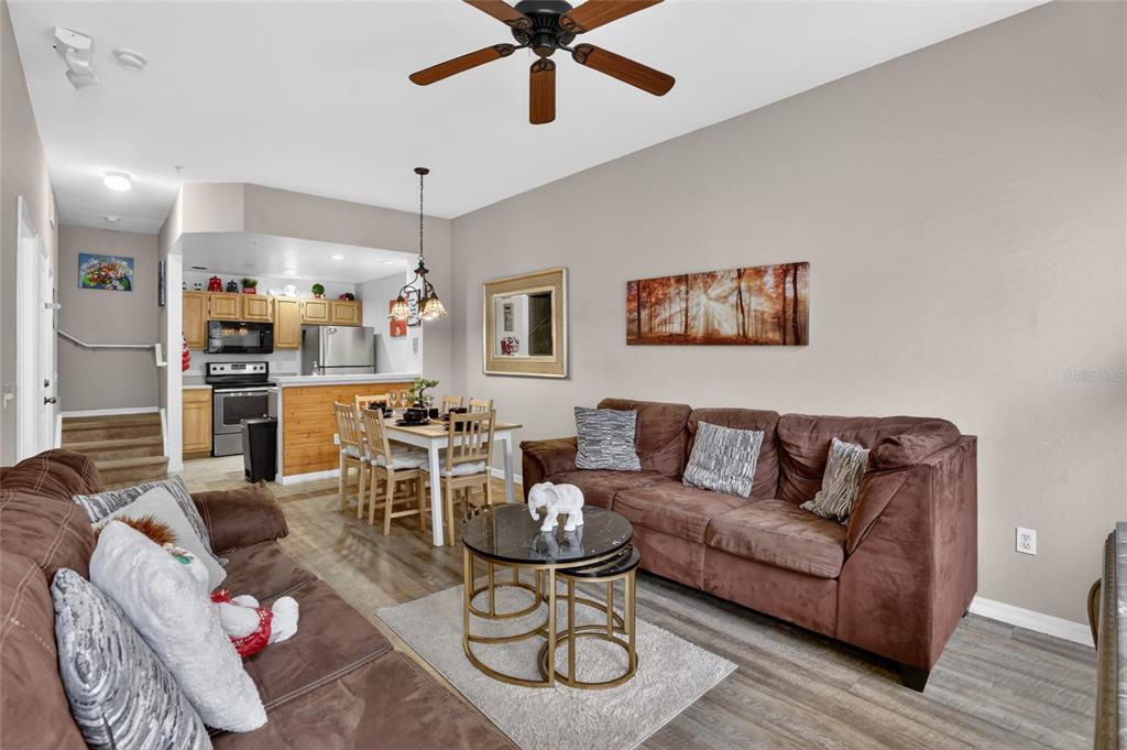 A living room and dining area feature brown sofas, a coffee table, and wood-look flooring — 4006 SAN GALLO DRIVE UNIT 104, KISSIMMEE, FL
