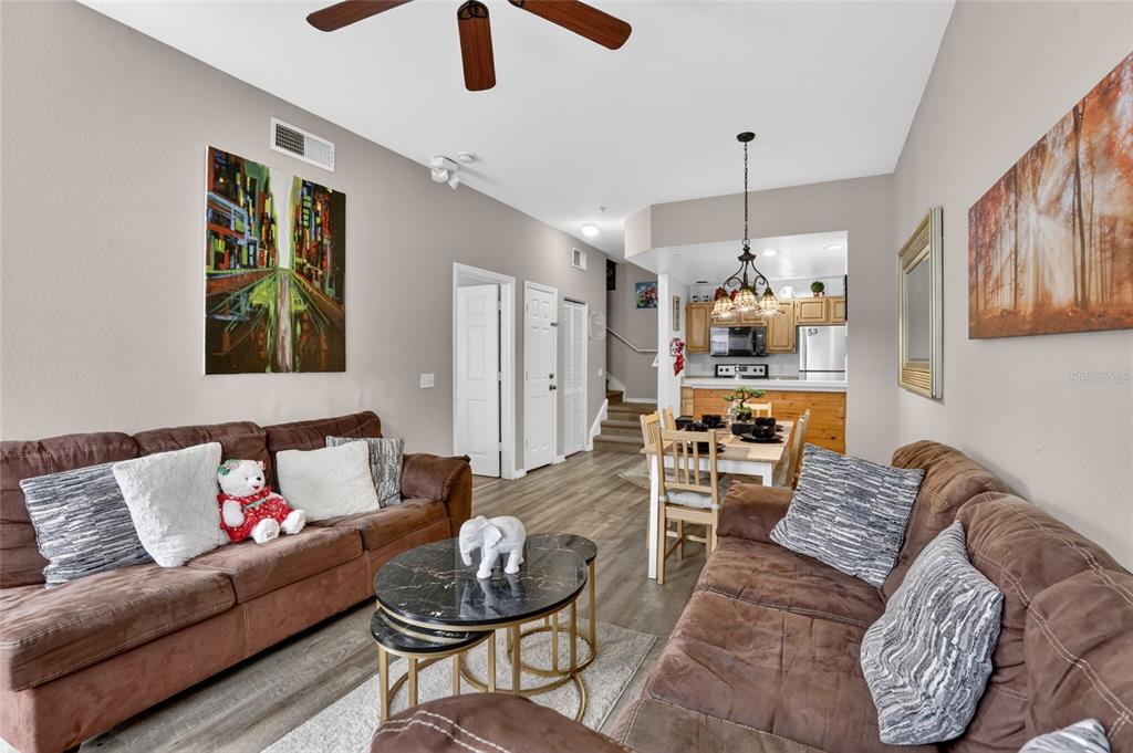 A living room with brown sofas, a marble coffee table, and an adjacent dining area — 4006 SAN GALLO DRIVE UNIT 104, KISSIMMEE, FL