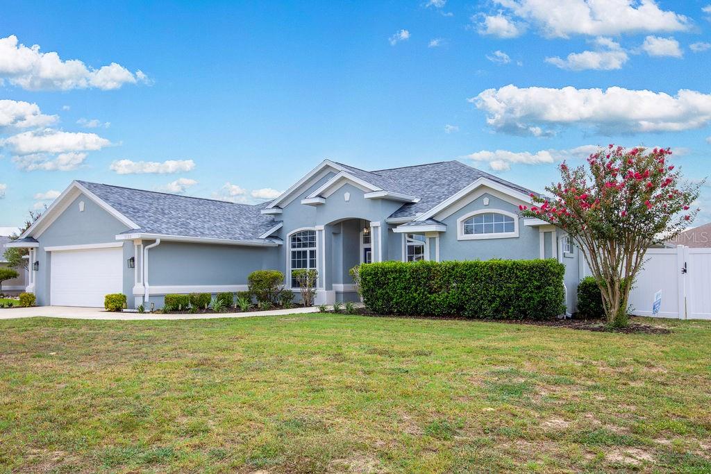 A single-story light blue house with a two-car garage and a manicured front lawn — 5580 SW 81ST PLACE, OCALA, FL