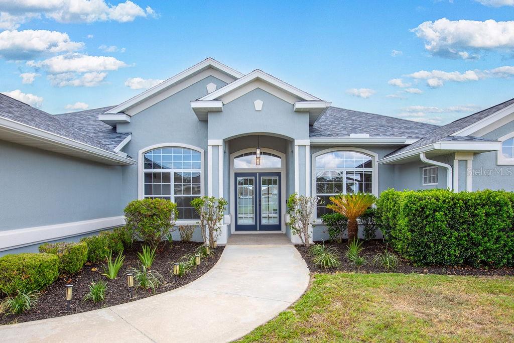 A light blue house exterior features a concrete walkway leading to a double front door — 5580 SW 81ST PLACE, OCALA, FL