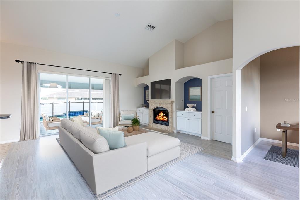 A living room features a fireplace, built-in shelving, a sectional sofa, and sliding glass doors — 5580 SW 81ST PLACE, OCALA, FL