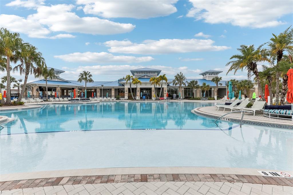 A resort-style swimming pool with a shallow entry area sits before a large clubhouse building — 297 JETTY WAY, DAVENPORT, FL