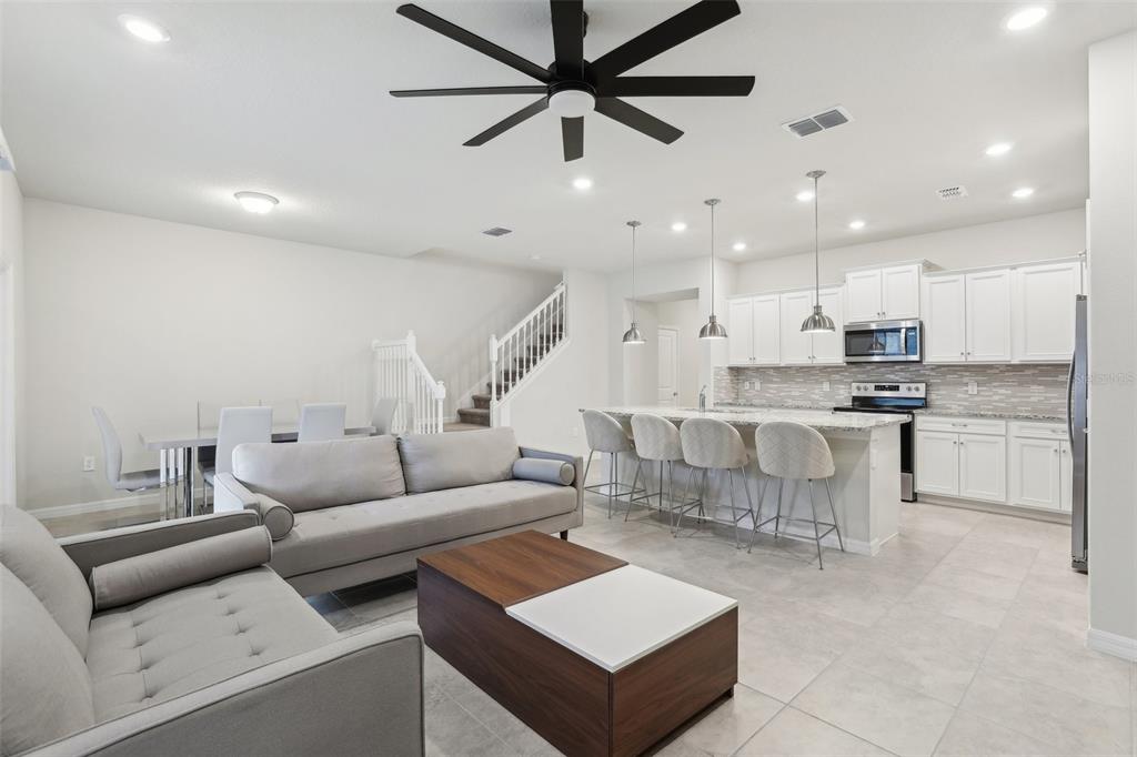 An open-concept living room and kitchen with white cabinets, a large island, and tile flooring — 297 JETTY WAY, DAVENPORT, FL