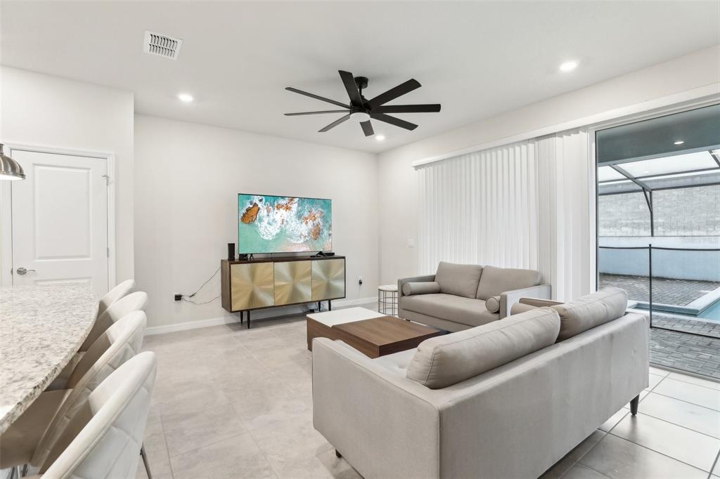 A living room features a grey sofa, a media console, and a ceiling fan — 297 JETTY WAY, DAVENPORT, FL