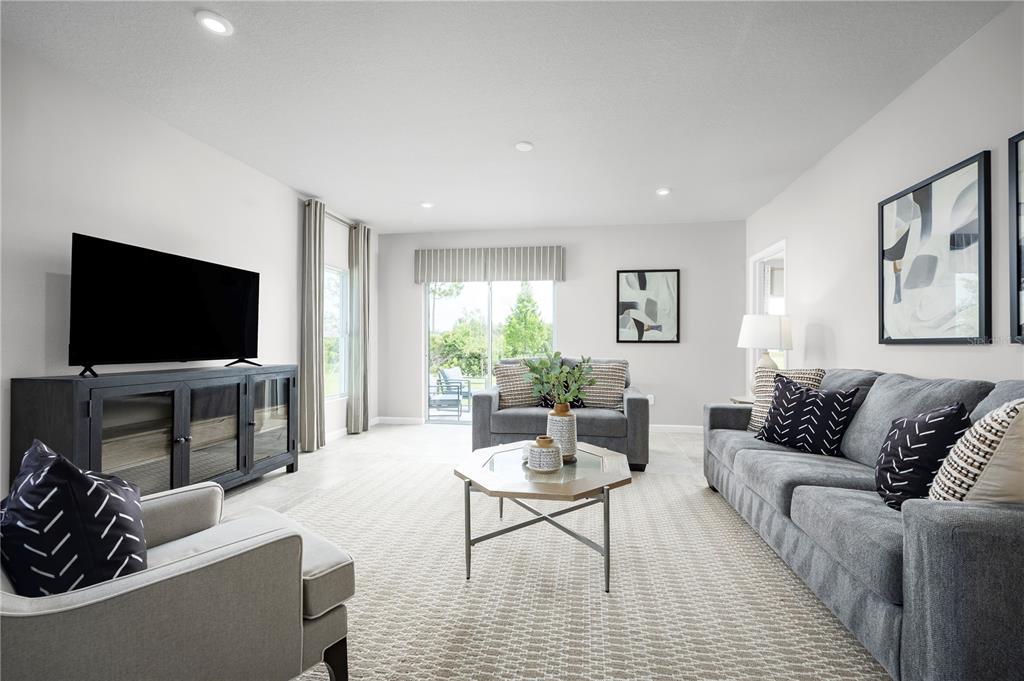 A living room features a gray sofa, armchair, television console, and a glass-topped coffee table — 6944 SUNDIAL DRIVE, LAKELAND, FL