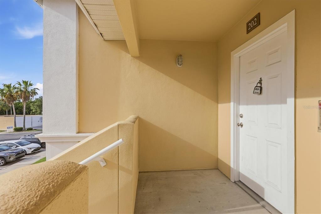 A covered exterior entryway features a white door labeled 202 and a concrete floor — 1015 VILLAGIO CIRCLE UNIT 202, SARASOTA, FL