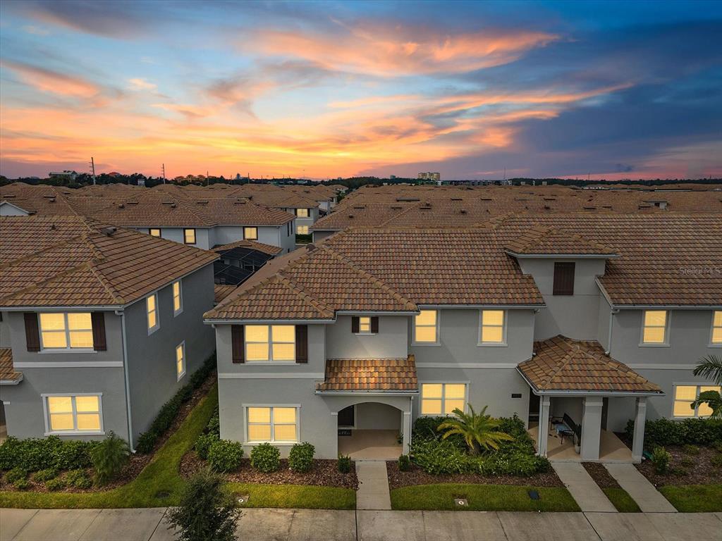 An aerial view of a suburban neighborhood featuring multi-story townhomes with tan tile roofs — 4823 DEDICATION STREET, KISSIMMEE, FL
