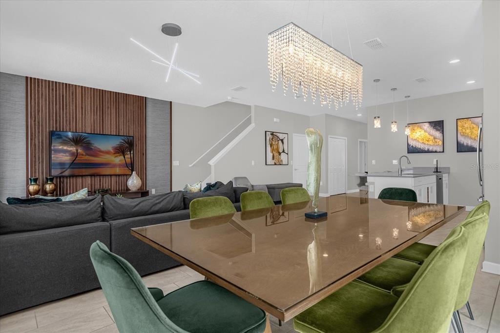 A dining area with a glass table and green chairs sits before a living room — 4823 DEDICATION STREET, KISSIMMEE, FL