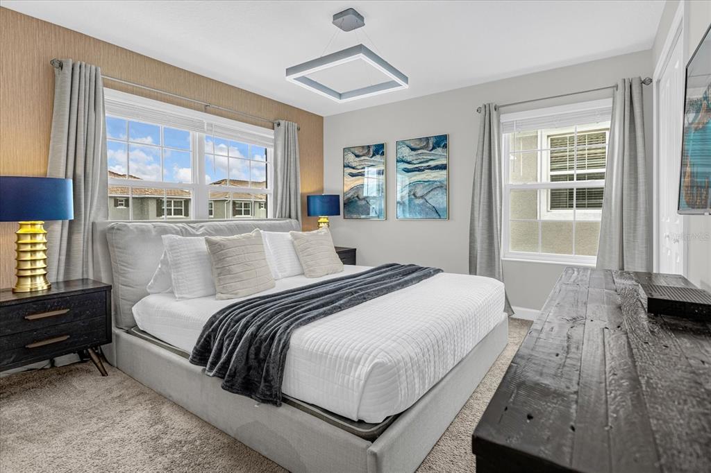 A bedroom features a king bed, dark wood furniture, blue lamps, and a modern light fixture — 4823 DEDICATION STREET, KISSIMMEE, FL