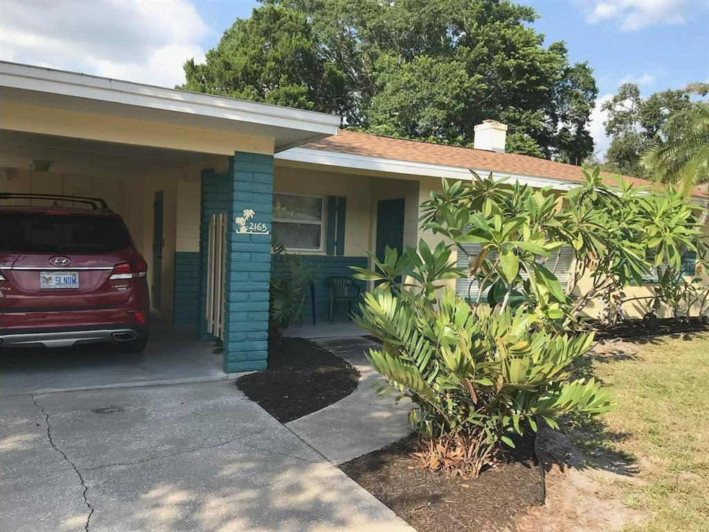A single-story house with a carport, teal brick accents, and a front yard with landscaping — 2165 SUNNYSIDE LANE, SARASOTA, FL