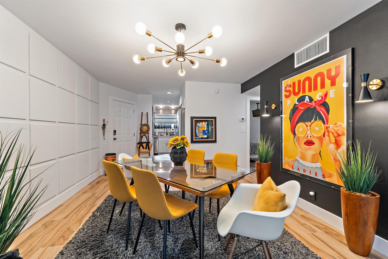 A dining room features a glass table, yellow chairs, a large poster, and a chandelier — 50 Celestial Way # 310, Juno Beach FL 33408, JUNO BEACH, FL