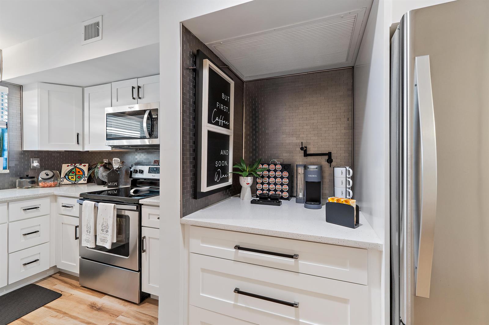 A kitchen features white cabinets, stainless steel appliances, and a dedicated coffee station with tile — 50 Celestial Way # 310, Juno Beach FL 33408, JUNO BEACH, FL