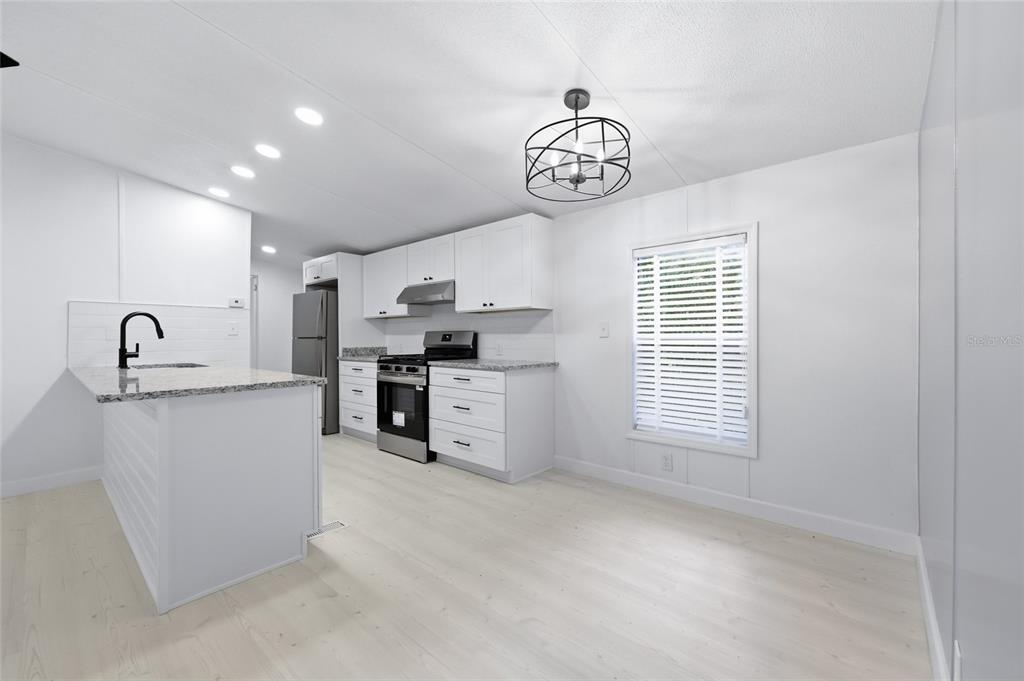 A modern kitchen features white cabinets, granite countertops, stainless steel appliances, and light wood flooring — 264 SW CENTRAL TERRACE, FORT WHITE, FL