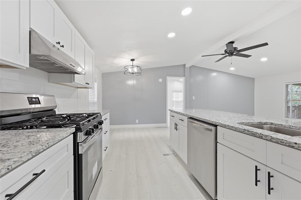 A modern kitchen features white cabinets, granite countertops, stainless steel appliances, and light wood flooring — 264 SW CENTRAL TERRACE, FORT WHITE, FL