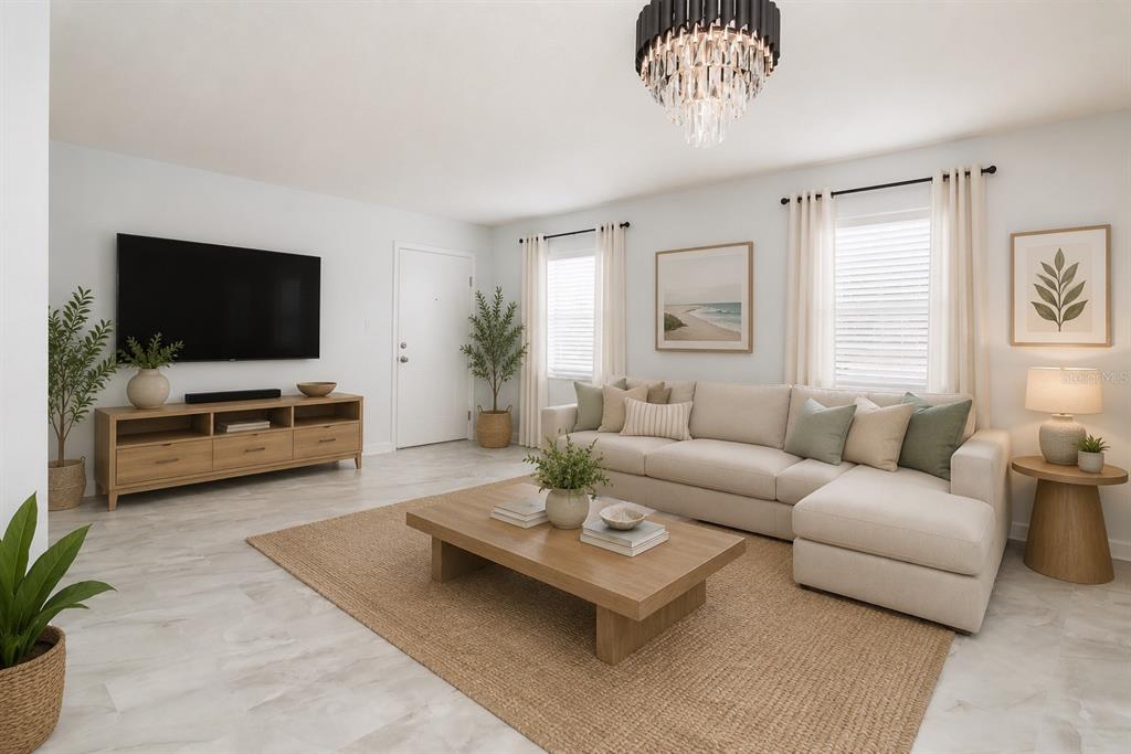 A bright living room features a beige sectional sofa, wood coffee table, and television console — 1115 RUE DES CHATEAUX UNIT 1A, SOUTH PASADENA, FL